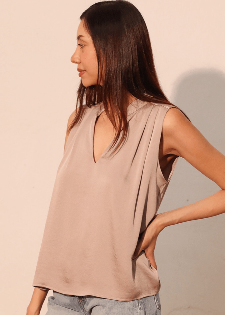 Elevate your wardrobe with this sophisticated taupe poly silk top, designed for effortless elegance. The sleeveless silhouette and flattering V-neckline create a refined look, while strategic pleating at the front and back adds subtle dimension and movement. 