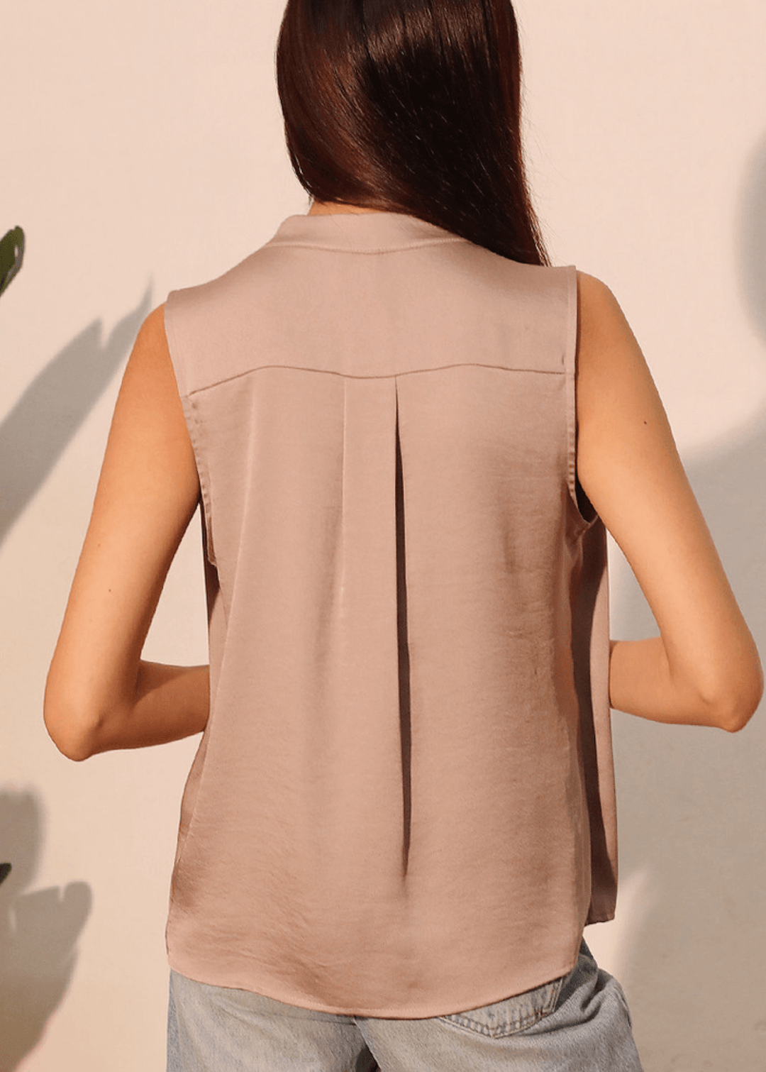 Elevate your wardrobe with this sophisticated taupe poly silk top, designed for effortless elegance. The sleeveless silhouette and flattering V-neckline create a refined look, while strategic pleating at the front and back adds subtle dimension and movement. 