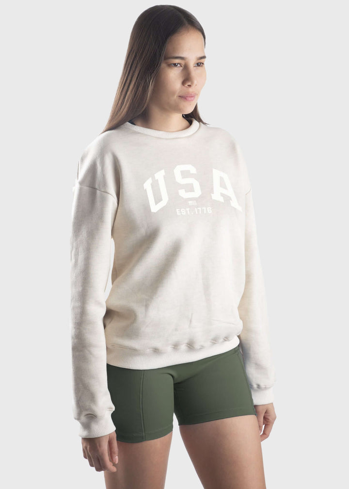 Experience all-day comfort with this USA Mid-Weight Fleece Sweatshirt. Crafted from a durable 14-ounce heavy-weight fleece, it offers warmth and breathability for cooler spring days. Featuring a loose fit, ribbed cuffs, and hem, this mid-layer is perfect for effortless layering. Show your pride with the classic white USA graphic, and enjoy the quality of a garment proudly made in the USA since 1990.