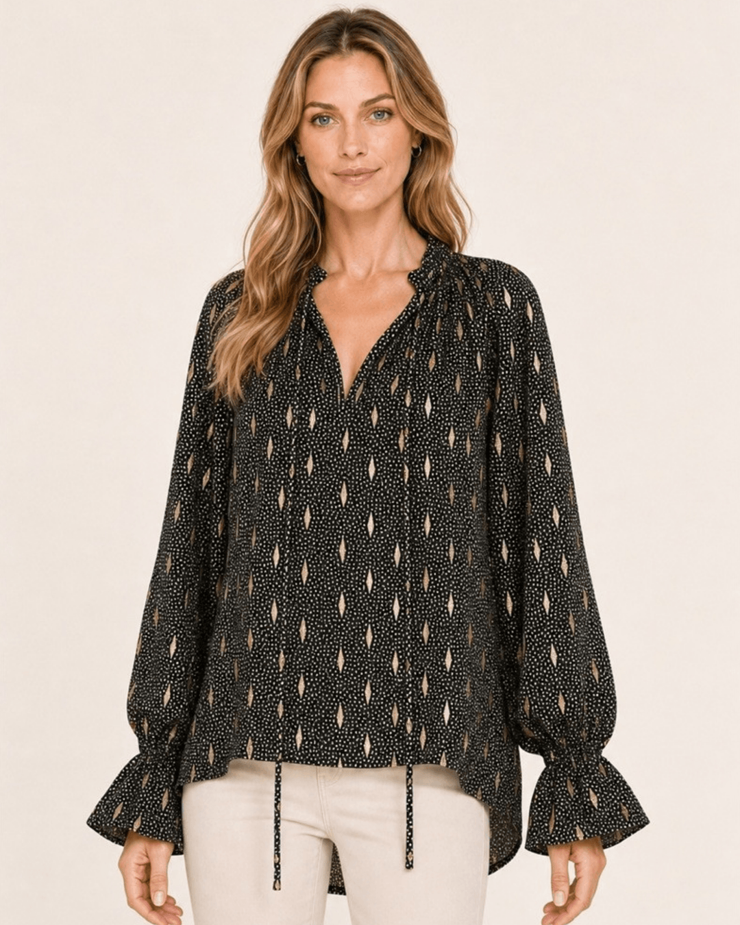 Made in USA Radiant Ruffle Neck Foil Print Blouse - Black: front view with cream pants, tie neck and ruffle cuffs