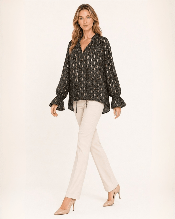 Made in USA Radiant Ruffle Neck Foil Print Blouse - Black: full-length walking view with cream pants and heels