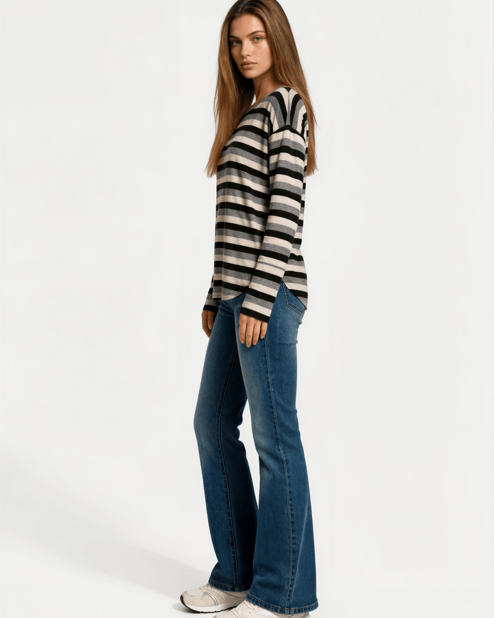 Made in USA Stella women’s grey, black, and cream striped long sleeve top with a round neckline, dropped shoulders, relaxed oversized fit, and rounded hem.