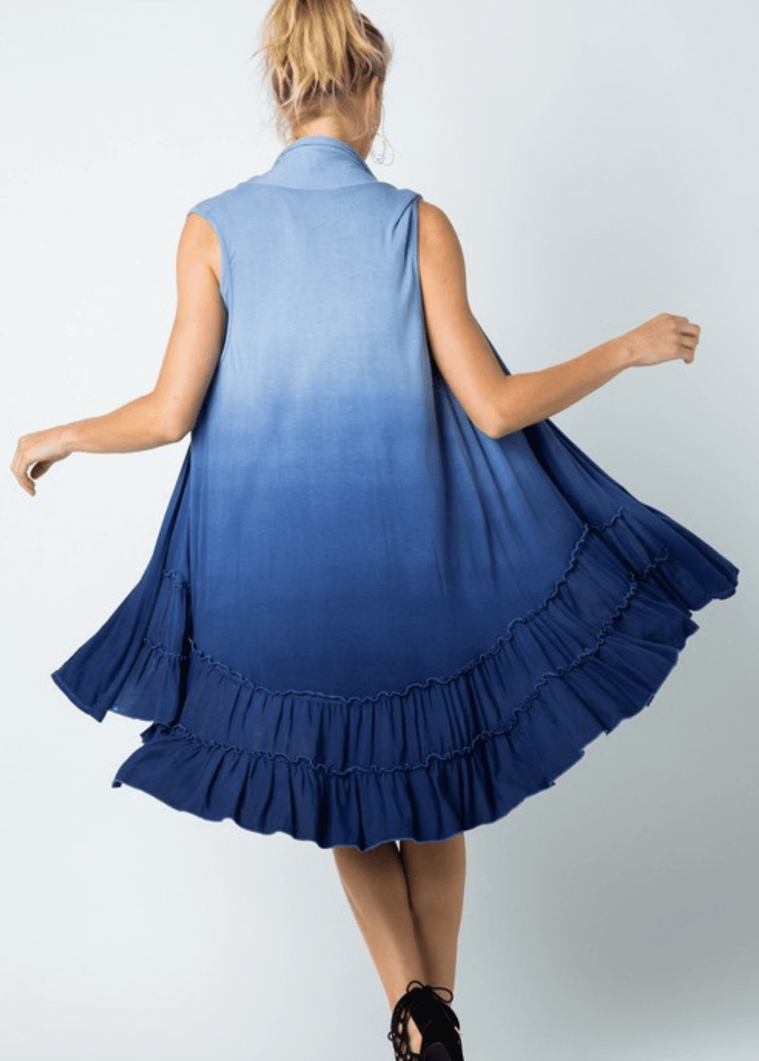 Blue ombre tie-dye meets effortless elegance in this versatile cardigan vest. Featuring a tiered ruffled hem and flowing silhouette, it transitions seamlessly from casual to dressed-up occasions. Crafted from a luxurious viscose-spandex blend for comfort and movement, this Made in USA piece is designed to flatter and inspire. 