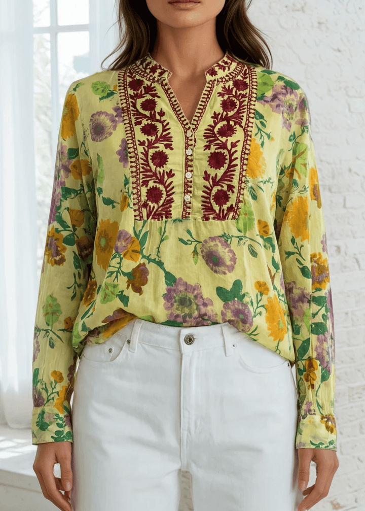 Bask in the beauty of effortless bohemian charm with the Carla Top. Crafted from soft, breathable cotton voile, this piece features a vibrant floral print in sun-kissed tones of golden marigold, lilac, and fresh green. The hand-embroidered deep red bib adds an artisanal touch, making each blouse unique. Designed with a relaxed silhouette and a flattering V-neckline, it&