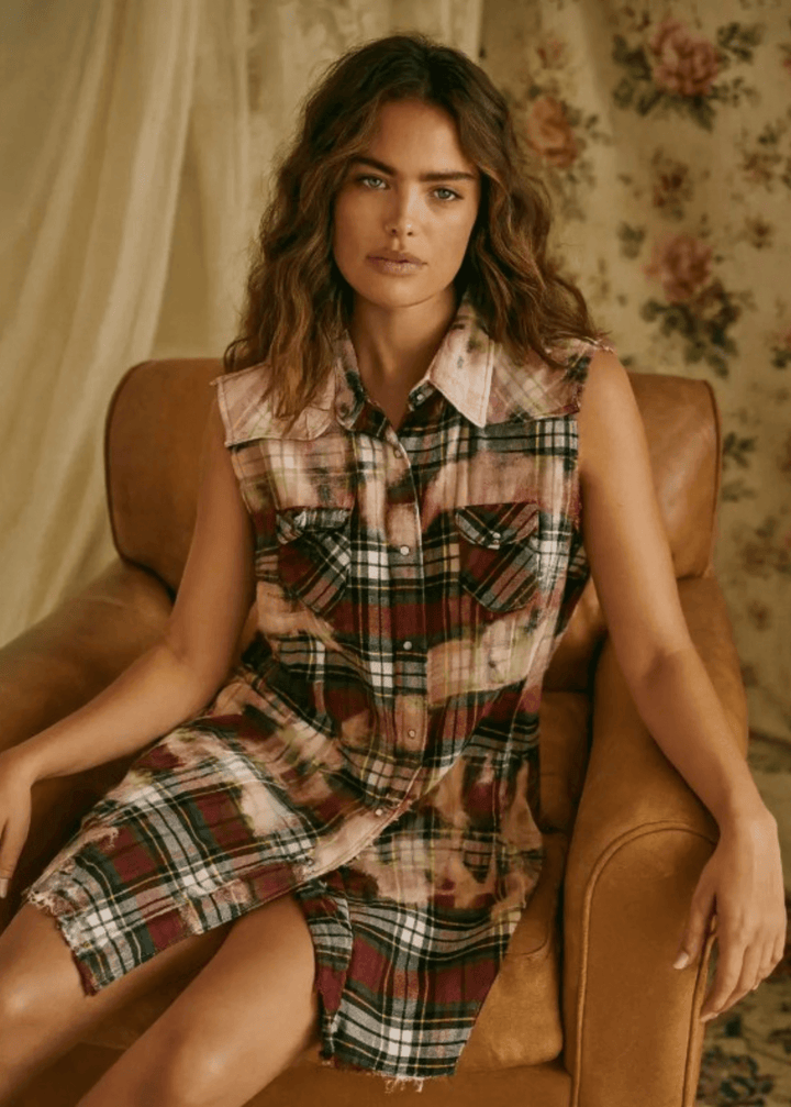Meet The Sedona Sunset Sleeveless Plaid Flannel Tunic - a sleeveless, boho-chic essential designed for effortless layering and laid-back luxury. Crafted in Los Angeles from ultra-soft, vintage-washed plaid, this one-of-a-kind piece features hand-bleached details, raw frayed edges, and classic chest pockets for a relaxed yet elevated vibe. Its tunic length makes it versatile enough to wear open over denim shorts or buttoned up as a dress.