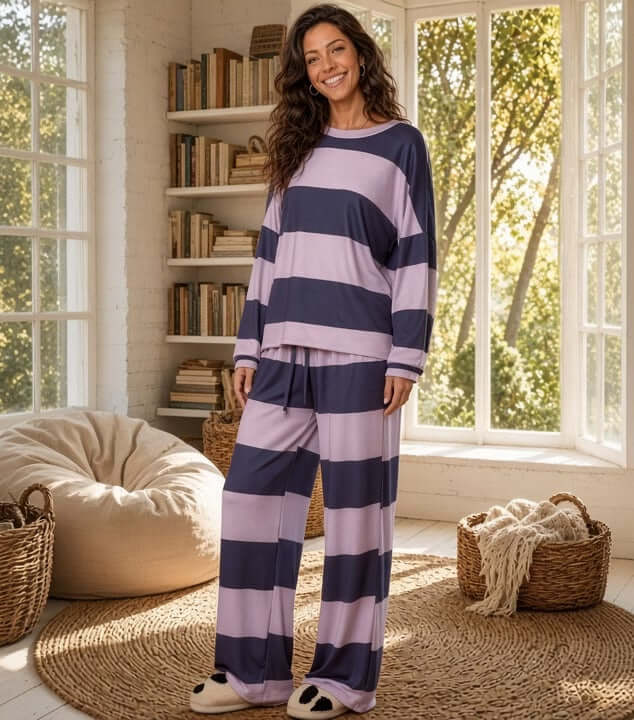 Made in USA women’s cozy navy and soft lavender pajama set with bold, wide horizontal stripes, a loose-fitting long-sleeve crewneck top, relaxed dropped shoulders, cuffed sleeves, and flowing full-length drawstring pants with gently flared legs.